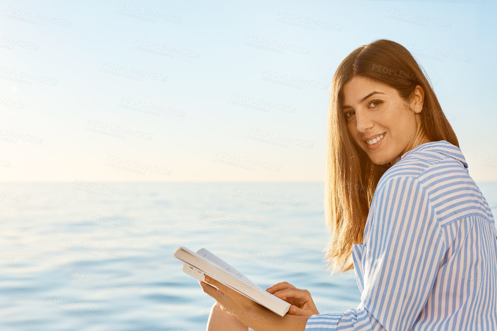 Buy stock photo Reading, portrait and space with happy woman at sea for holiday, travel or voyage in summer season. Book, confident and smile with tourist person outdoor by ocean for getaway or vacation at sunset