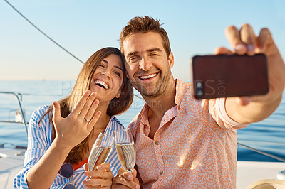 Buy stock photo Shot of a happy young couple taking a selfie of their engagement on an ocean cruise