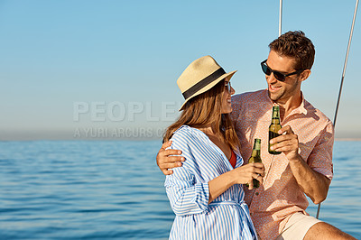Buy stock photo Shot of a young couple drinking beer together on an ocean cruise