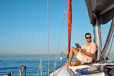 Buy stock photo Shot of a handsome young man using a digital tablet on a relaxing boat cruise