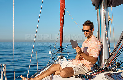 Buy stock photo Shot of a handsome young man using a digital tablet on a relaxing boat cruise