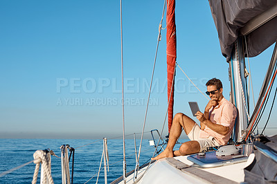 Buy stock photo Shot of a handsome young man using a digital tablet on a relaxing boat cruise
