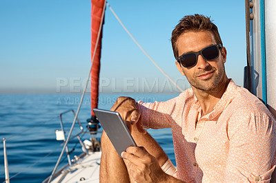 Buy stock photo Shot of a handsome young man using a digital tablet on a relaxing boat cruise