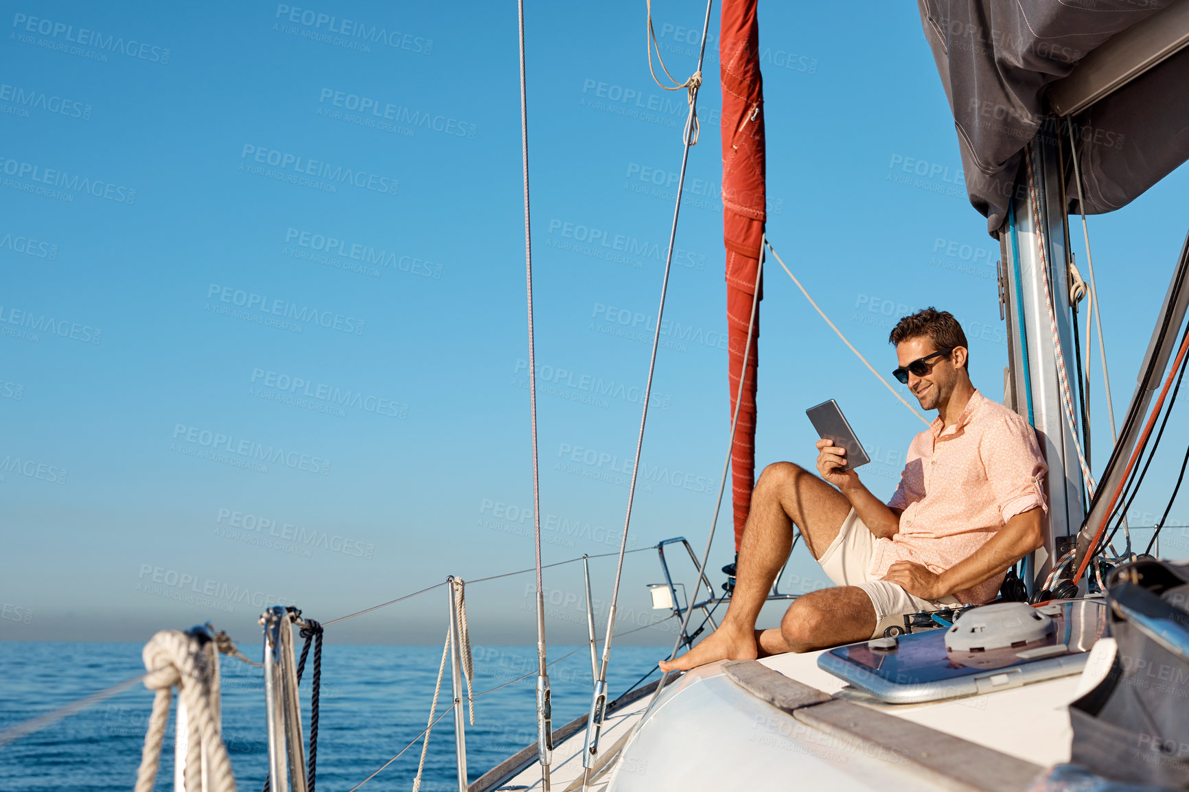 Buy stock photo Shot of a handsome young man using a digital tablet on a relaxing boat cruise