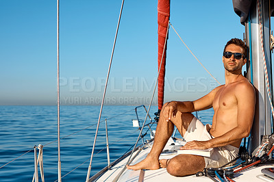 Buy stock photo Shot of a handsome young man reading a book on a relaxing boat cruise