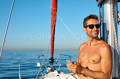Buy stock photo Shot of a handsome young man using a mobile phone on a relaxing boat cruise