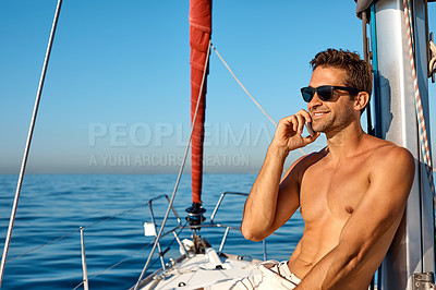Buy stock photo Shot of a handsome young man using a mobile phone on a relaxing boat cruise