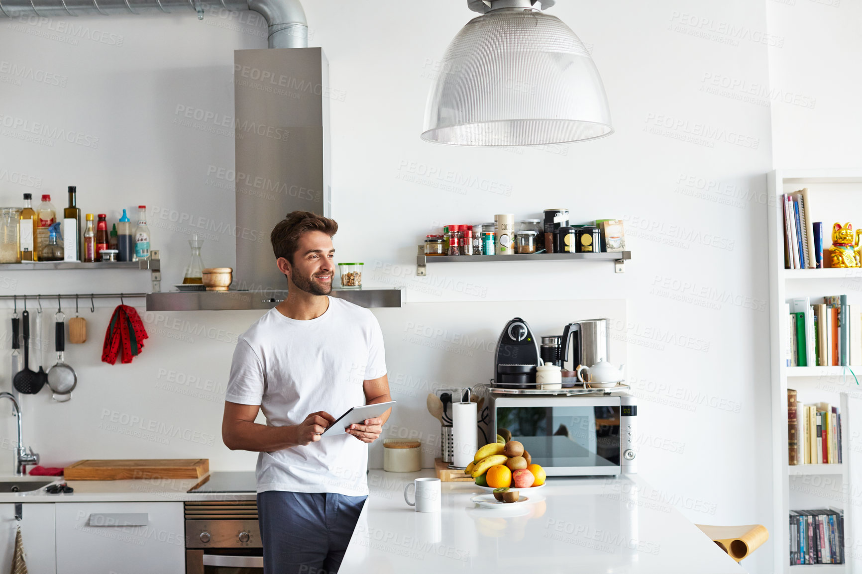 Buy stock photo Shot of a handsome young man using a digital tablet in the morning at home
