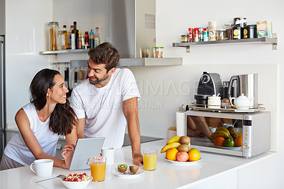 Buy stock photo Shot of a young couple using a digital tablet together during their morning routine at home