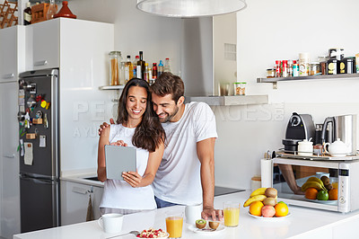 Buy stock photo Shot of a young couple using a digital tablet together during their morning routine at home