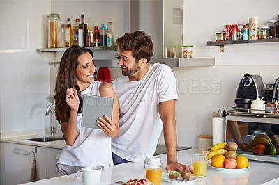 Buy stock photo Shot of a young couple using a digital tablet together during their morning routine at home