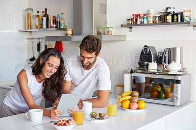 Buy stock photo Shot of a young couple using a digital tablet together during their morning routine at home