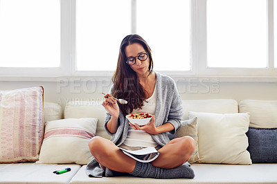 Buy stock photo Shot of a beautiful young woman going over some work while having breakfast in the morning at home