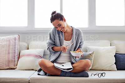 Buy stock photo Shot of a beautiful young woman talking on a mobile phone and working while having breakfast at home