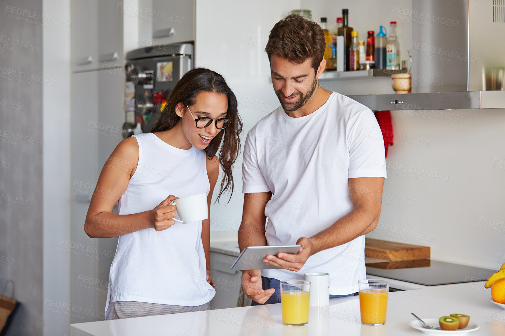 Buy stock photo Shot of a young couple using a digital tablet together during their morning routine at home