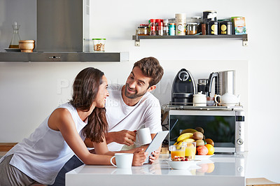 Buy stock photo Shot of a young couple using a digital tablet together during their morning routine at home