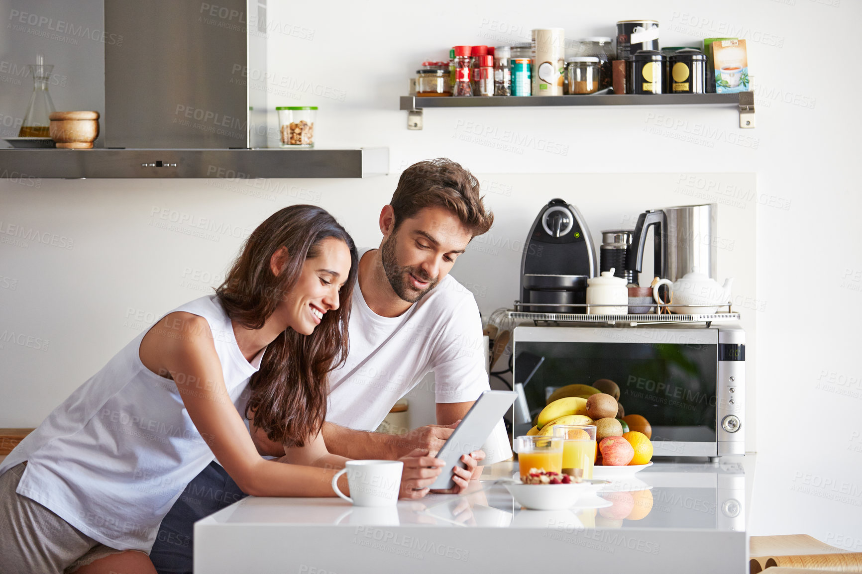 Buy stock photo Breakfast, relax and tablet with happy couple in kitchen of home together for morning routine. Food, scrolling and smile with people at counter in apartment for health recipe, nutrition or wellness