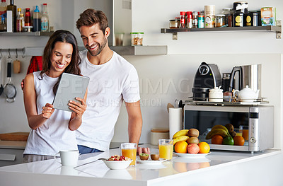 Buy stock photo Shot of a young couple using a digital tablet together during their morning routine at home