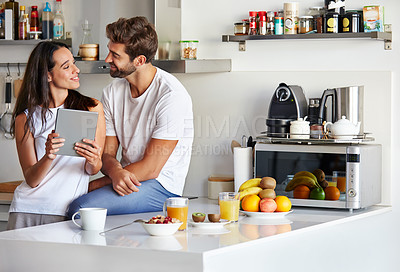 Buy stock photo Shot of a young couple using a digital tablet together during their morning routine at home