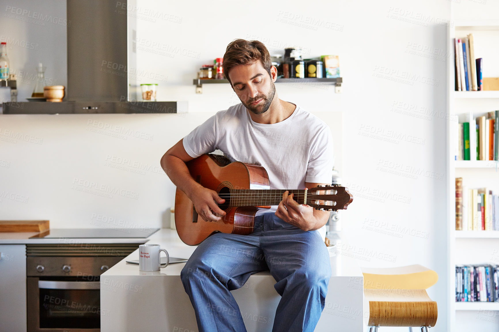 Buy stock photo Shot of a handsome young man playing the guitar in the morning at home