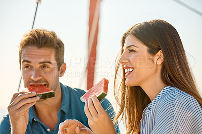 Buy stock photo Shot of a happy young couple eating watermelon on a relaxing ocean cruise