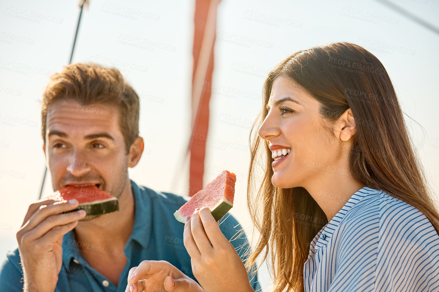 Buy stock photo Shot of a happy young couple eating watermelon on a relaxing ocean cruise