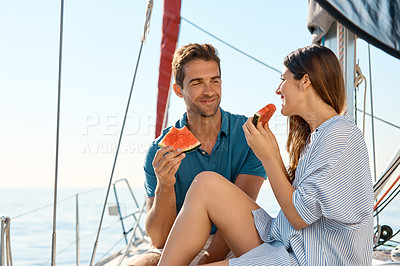Buy stock photo Shot of a happy young couple eating watermelon on a relaxing ocean cruise