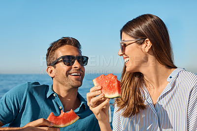 Buy stock photo Shot of a happy young couple eating watermelon on a relaxing ocean cruise
