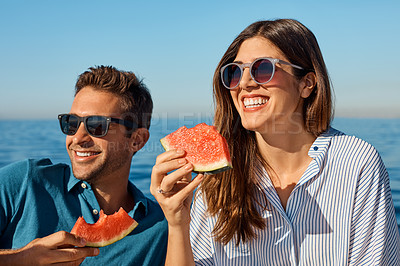 Buy stock photo Shot of a happy young couple eating watermelon on a relaxing ocean cruise