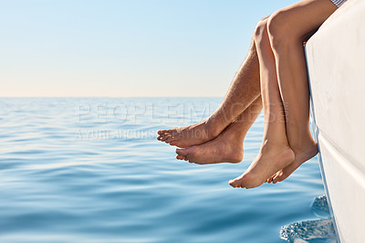 Buy stock photo Cropped shot of a couple sitting with their feet off the side of boat on a cruise