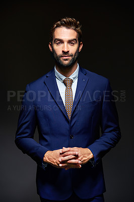 Buy stock photo Studio portrait of a handsome young businessman posing against a dark background