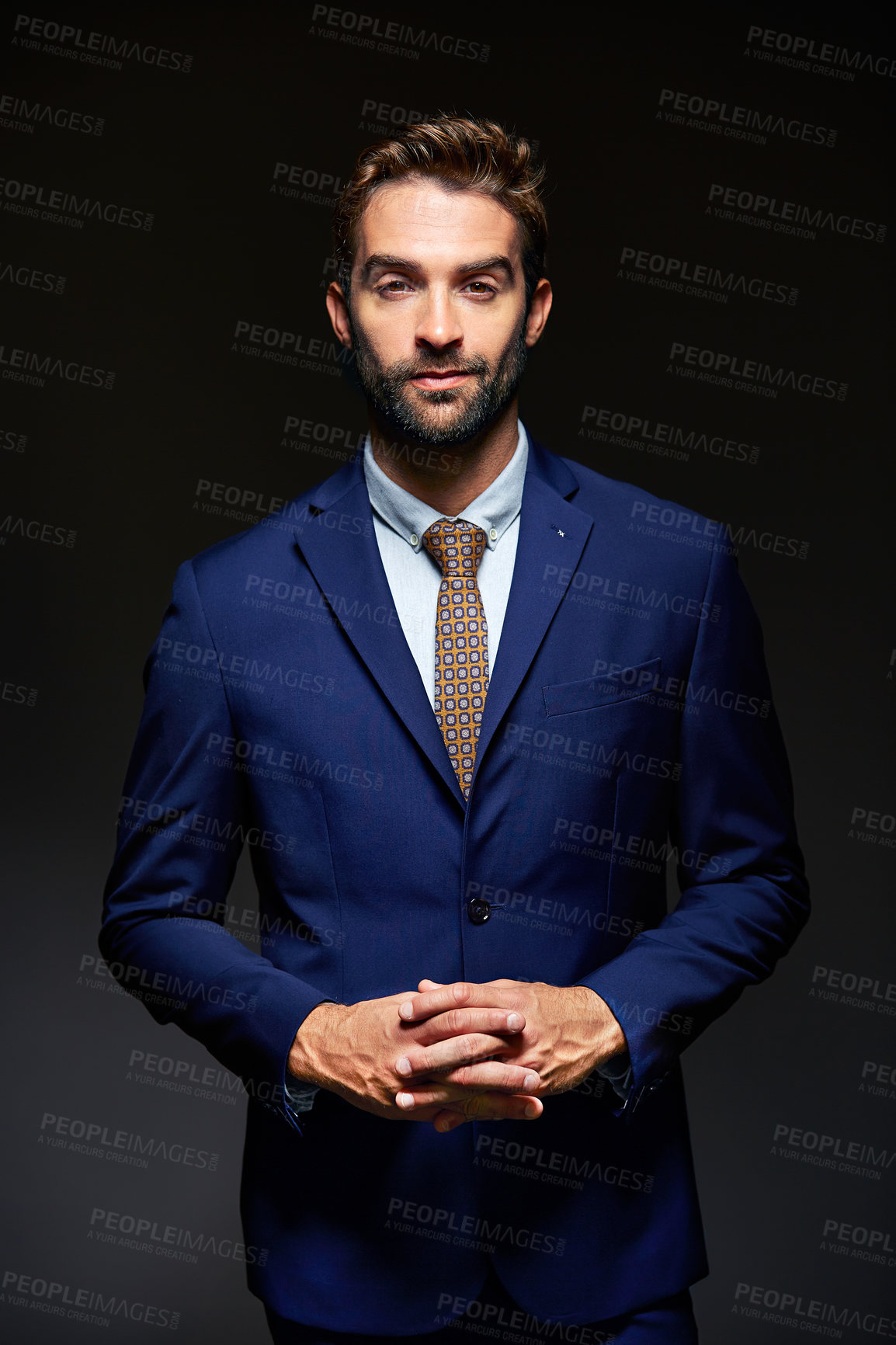 Buy stock photo Studio portrait of a handsome young businessman posing against a dark background