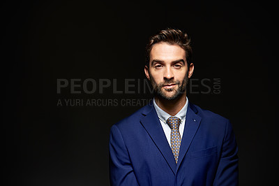 Buy stock photo Studio portrait of a handsome young businessman posing against a dark background