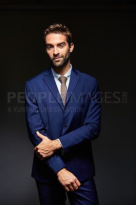 Buy stock photo Studio portrait of a handsome young businessman posing against a dark background