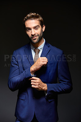 Buy stock photo Studio portrait of a handsome young businessman posing against a dark background