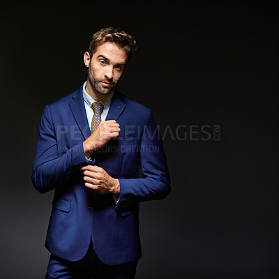 Buy stock photo Studio portrait of a handsome young businessman posing against a dark background