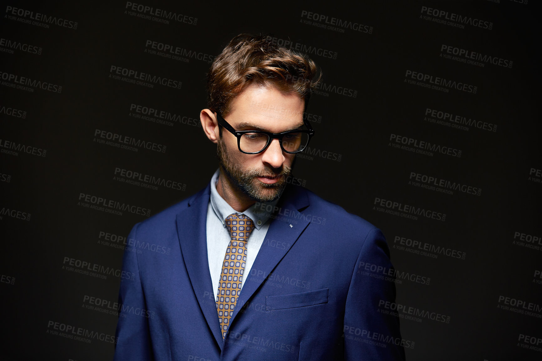 Buy stock photo Studio shot of a handsome young businessman posing against a dark background