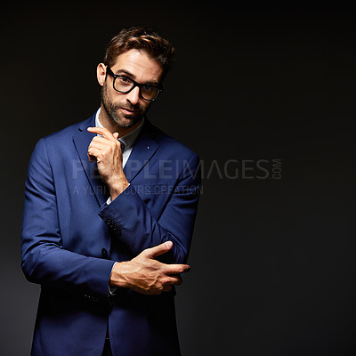 Buy stock photo Studio portrait of a handsome young businessman posing against a dark background