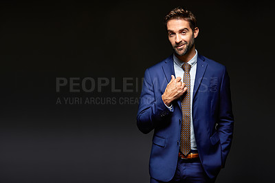Buy stock photo Studio portrait of a handsome young businessman posing against a dark background