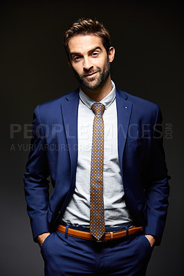 Buy stock photo Studio portrait of a handsome young businessman posing against a dark background