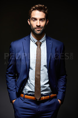 Buy stock photo Studio portrait of a handsome young businessman posing against a dark background
