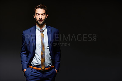 Buy stock photo Studio portrait of a handsome young businessman posing against a dark background