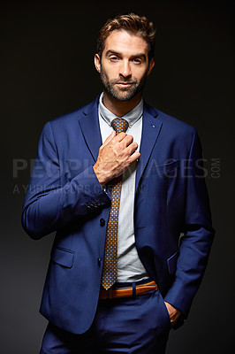 Buy stock photo Studio portrait of a handsome young businessman posing against a dark background
