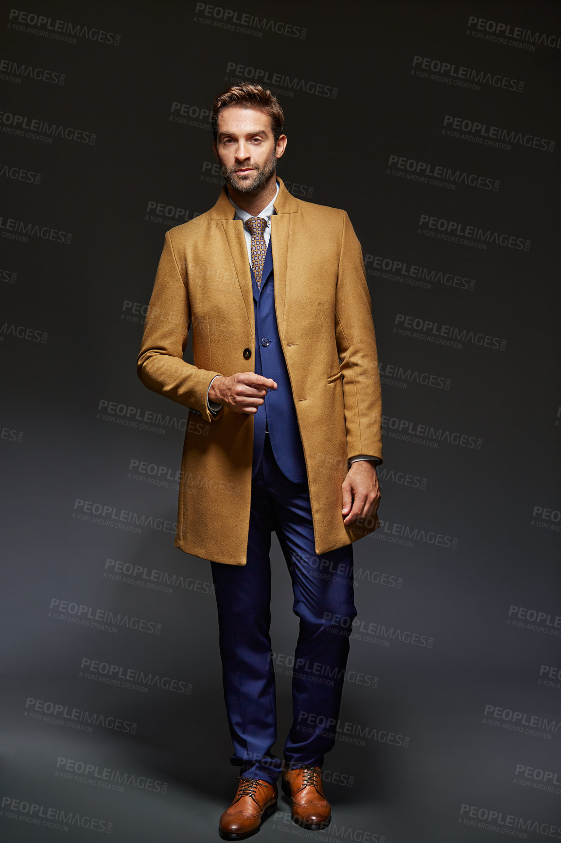 Buy stock photo Studio portrait of a handsome young businessman posing against a dark background