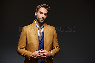 Buy stock photo Studio portrait of a handsome young businessman posing against a dark background