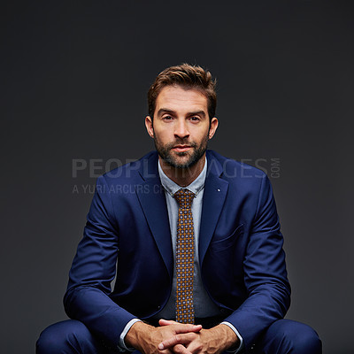 Buy stock photo Studio portrait of a handsome young businessman sitting against a grey background