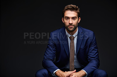 Buy stock photo Studio portrait of a handsome young businessman sitting against a grey background