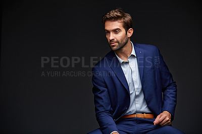 Buy stock photo Studio shot of a handsome young businessman sitting against a grey background