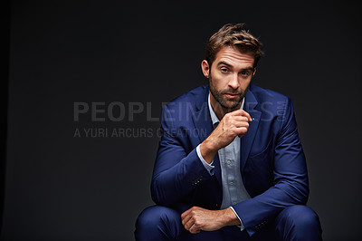 Buy stock photo Studio portrait of a handsome young businessman sitting against a grey background