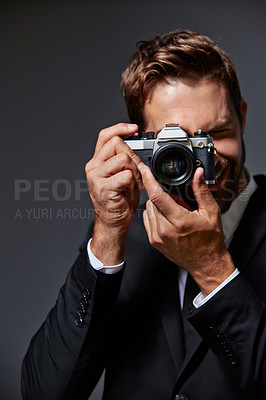 Buy stock photo Studio portrait of a handsome young man taking pictures against a grey background